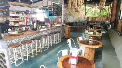 a bar with wooden tables and white chairs at Igloo Beach Lodge in Manuel Antonio