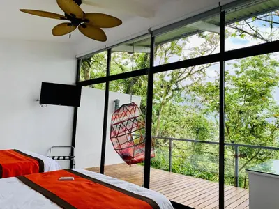 a bedroom with a large window and a hammock at Sangregado Lodge in Fortuna