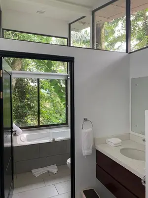 a bathroom with a tub and a sink and a mirror at Sangregado Lodge in Fortuna