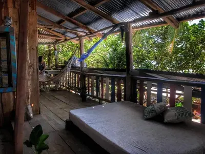 a porch with a bed and a hammock on it at Surfhost in Garza