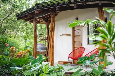 a porch with two red chairs and trees at SoulShine in Playa Avellana