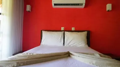 a bedroom with a red wall and a bed with white pillows at Hotel Poza Blanca Lodge in San Mateo