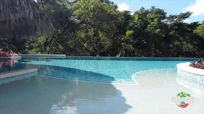 a swimming pool with blue water and trees in the background at Hotel Poza Blanca Lodge in San Mateo
