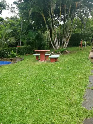 a picnic table and benches in the grass at Pochote Lodge in Hacienda Guayabo
