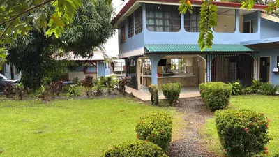 a house with a green awning in a yard at Yubarta Lodge in Uvita