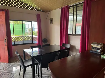 a dining room with a table and chairs and pink curtains at Yubarta Lodge in Uvita