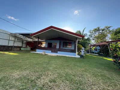 a house with a grass yard in front of it at Yubarta Lodge in Uvita
