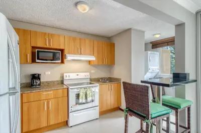 a kitchen with wooden cabinets and a white stove top oven at Costa Linda 7-13 in Jacó