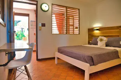 a bedroom with a bed and a table and a clock at Samara Pacific Lodge in Sámara