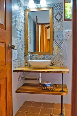 a bathroom with a sink and a mirror on a shelf at Samara Pacific Lodge in Sámara