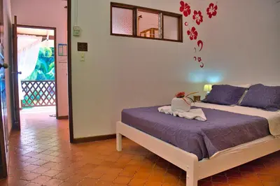 a bedroom with a bed with purple sheets and flowers on the wall at Samara Pacific Lodge in Sámara