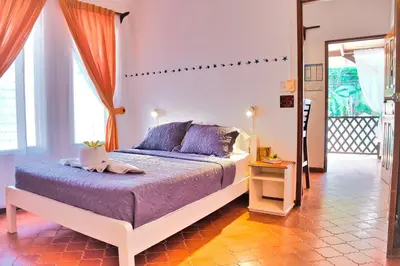 a bedroom with a bed with purple sheets and a window at Samara Pacific Lodge in Sámara