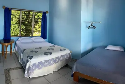 a blue room with two beds and a window at El Paraiso Azul in Ojochal