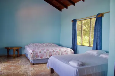a blue room with two beds and a window at El Paraiso Azul in Ojochal