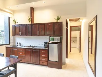 a kitchen with wooden cabinets and a table and a microwave at Surfside Apartments - Playa Carmen in Santa Teresa Beach