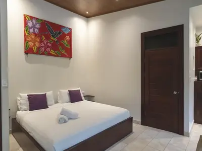 a bedroom with a bed with a painting on the wall at Surfside Apartments - Playa Carmen in Santa Teresa Beach