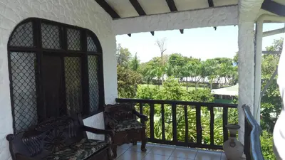 a porch with a chair and a balcony with a view at Hotel Arboleda in Quepos