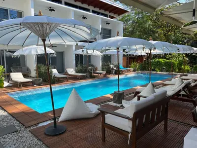 a pool with white chairs and umbrellas next to a pool at Ride On! Surf Hotel in Nosara