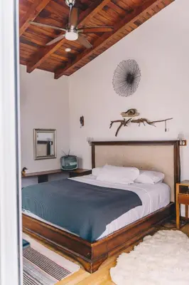a bedroom with a large bed and a ceiling at Ride On! Surf Hotel in Nosara
