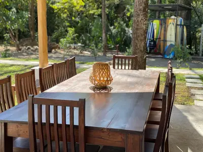 a wooden table with chairs and a vase on it at Ride On! Surf Hotel in Nosara