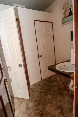 a bathroom with a white door and a sink at Costa Linda Art Hostel in Manuel Antonio