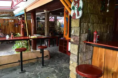 a bar in a restaurant with stools in front of it at Costa Linda Art Hostel in Manuel Antonio