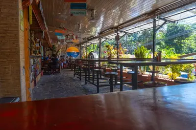 a bar with tables and chairs in a restaurant at Costa Linda Art Hostel in Manuel Antonio