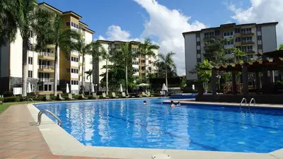 a large swimming pool with palm trees and buildings at 3Room Penthouse Beach Condo in Jacó