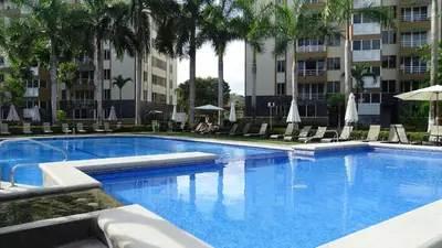 a large swimming pool with chairs and palm trees at 3Room Penthouse Beach Condo in Jacó