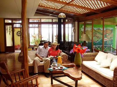 a man and woman sitting on a couch in a living room at Guayabo Lodge in Santa Cruz