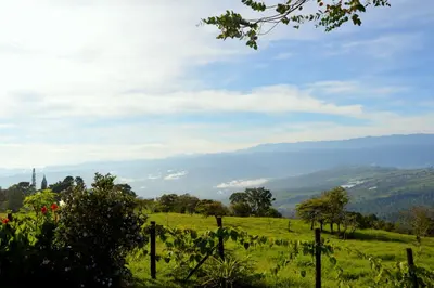 a field with a fence and mountains in the background at Guayabo Lodge in Santa Cruz