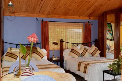 a bedroom with two beds and a vase with a flower on a table at Guayabo Lodge in Santa Cruz