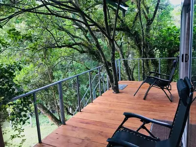 a porch with two chairs and a tree on it at Cabaña treehouse Mountain View in San Isidro