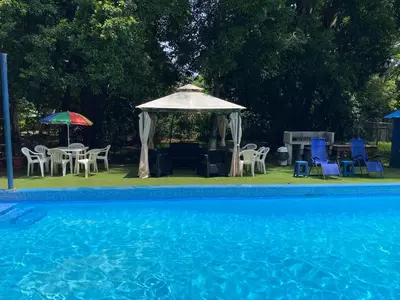 a pool with a gazebo and chairs and a table and umbrella at CASA TIPO QUINTA De ESPARCIMIENTO ANTIGUA TIPO VINTAG in Orotina