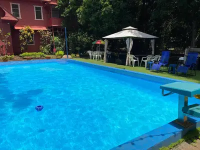 a blue swimming pool with chairs and an umbrella at CASA TIPO QUINTA De ESPARCIMIENTO ANTIGUA TIPO VINTAG in Orotina