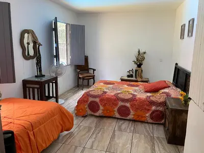 a bedroom with a bed with an orange blanket at CASA TIPO QUINTA De ESPARCIMIENTO ANTIGUA TIPO VINTAG in Orotina