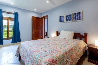 a bedroom with a bed with blue walls and a window at Ocean-View 2-BD Condo with Pool in Playa Flamingo