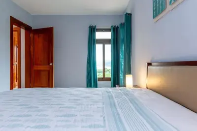 a bedroom with a bed with green curtains and a window at 2-BD with Ocean-View Terrace and Pool in Playa Flamingo