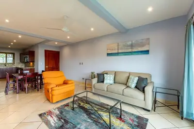 a living room with a couch and a table at 2-BD with Ocean-View Terrace and Pool in Playa Flamingo