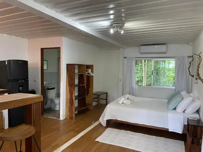 a bedroom with a white bed and a window at Nahele Lodge in Santa Teresa Beach