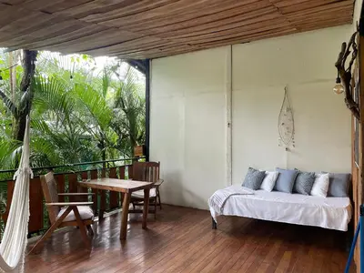 a bedroom with a bed and a table on a balcony at Nahele Lodge in Santa Teresa Beach