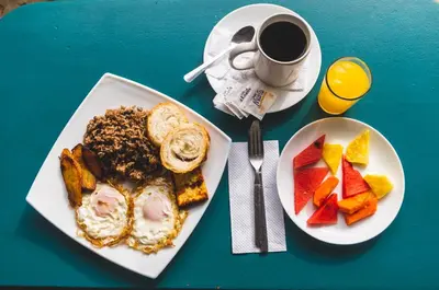 a table with two plates of food and a cup of coffee at Cabinas EL PRADO in San Isidro