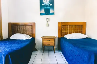 two beds in a room with blue sheets and a table at Cabinas EL PRADO in San Isidro