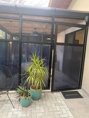 an open sliding glass door with two potted plants at Bungle in the Jungle in Playa Panama
