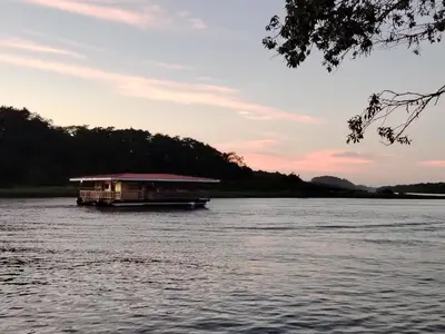 a boat on a river with a house on it at Cabinas ensueños in Tortuguero
