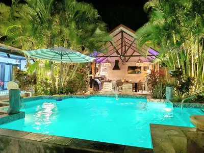a swimming pool with an umbrella in front of a house at Suite Paraiso Azul in Tamarindo