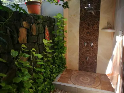 a bathroom with a stone wall and a shower at Suite Paraiso Azul in Tamarindo
