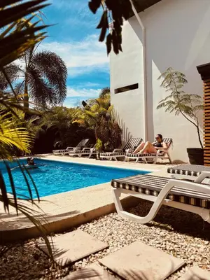 a woman sitting in a chair next to a swimming pool at Hotel Daleese in Uvita