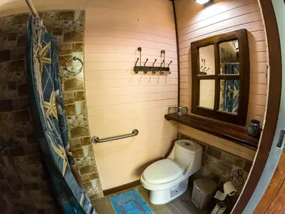 a bathroom with a toilet and a mirror at Coyote Rooms in Cabuya