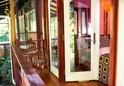 an open door to a porch with a chair on a house at Coyote Rooms in Cabuya